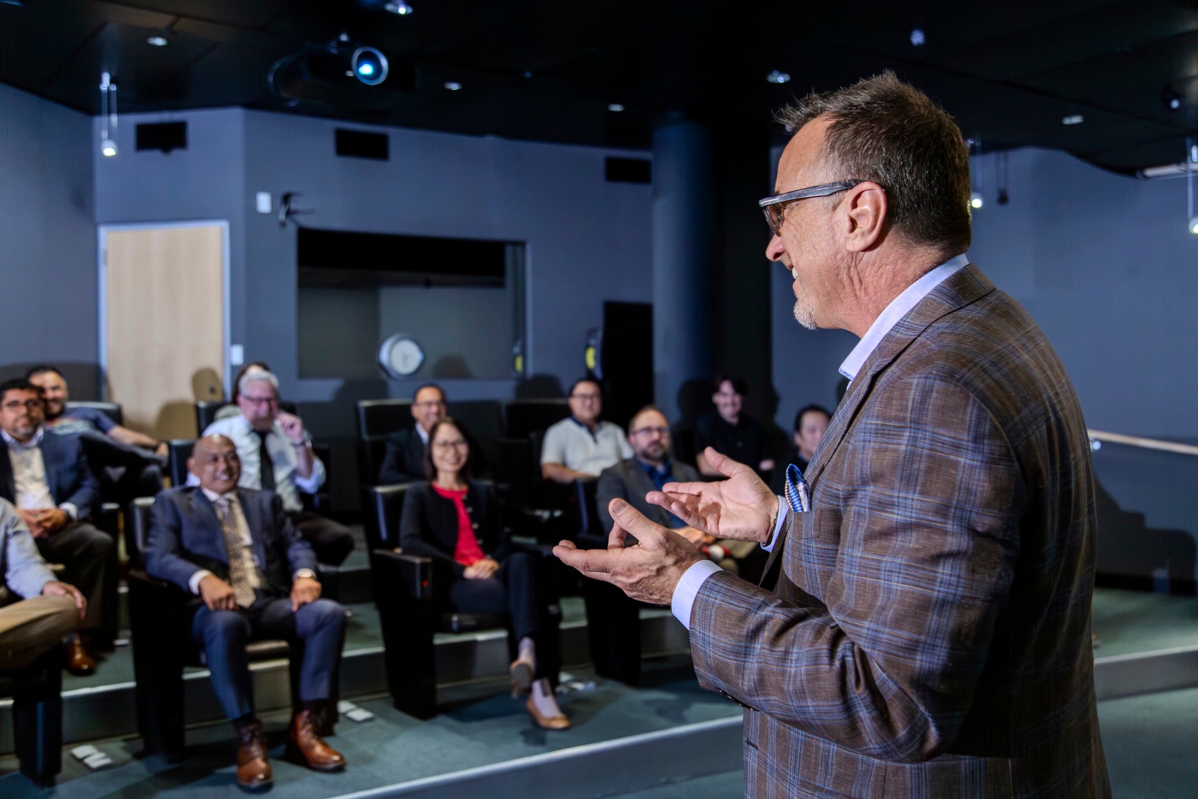 Ron Glickman addressing a seated room of executives, mid-point.